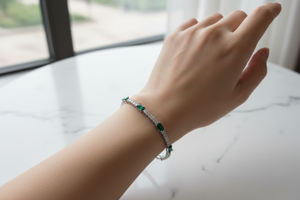 Emerald and diamond bracelet on model's wrist